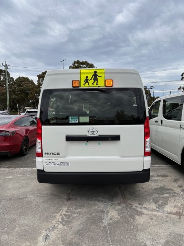 Photo of the rear of a 2023 6th generation Toyota HiAce Commuter bus with Safebus surface mount Victorian school bus lights and signage installed