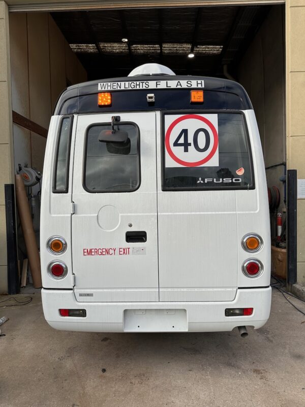 Photo of the back of a Mitsubishi Rosa bus with NSW TS150 school bus lights and signage installed