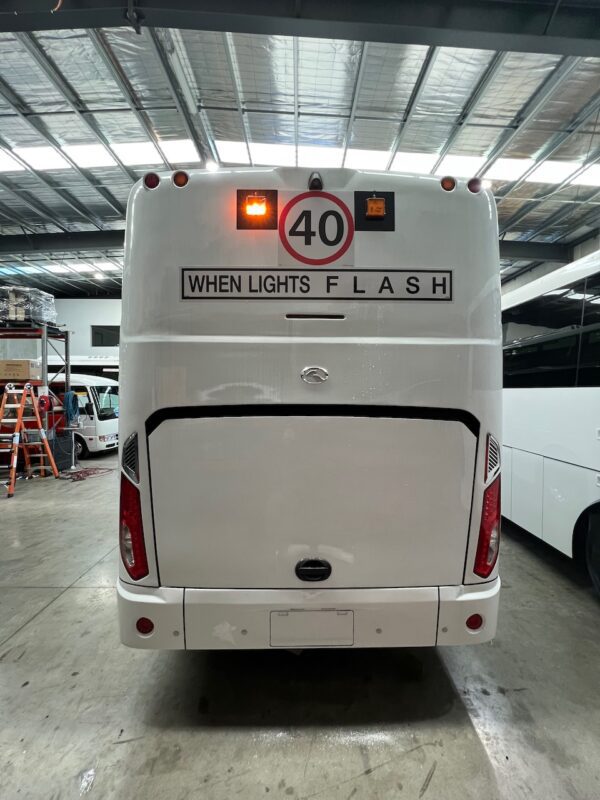 Photo of the rear of a 2024 King Long bus with New South Wales TS150 Safebus SB001A surface mount school bus lights and signage