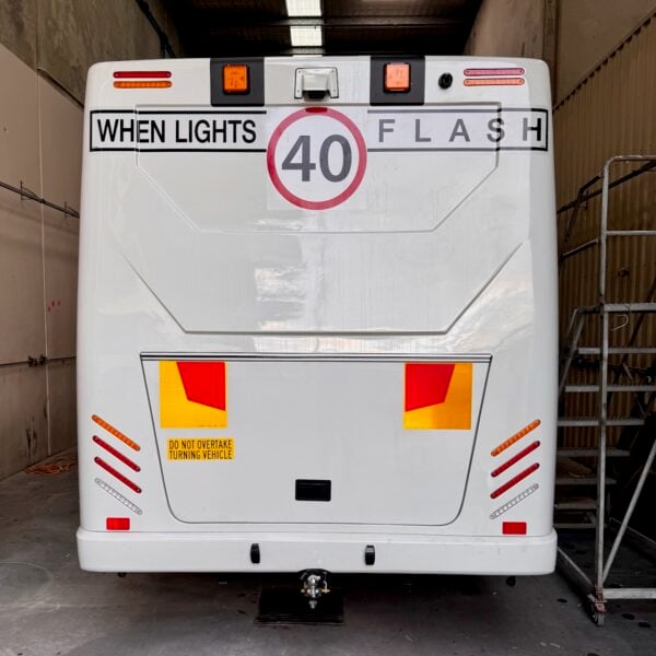 Photo of the rear of a 2024 Isuzu iBus with New South Wales TS150 Safebus SB001A surface mount school bus lights and signage