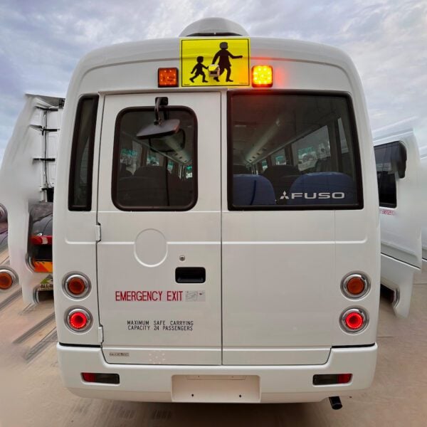 Photo of the rear of a 2024 5th generation BE7 Mitsubishi Rosa bus with Safebus SB001A surface mount Victorian school bus lights and mother & child sign installed