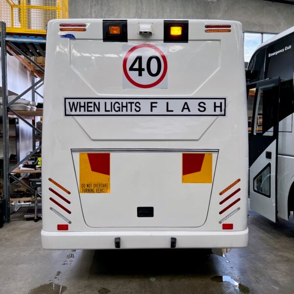 Photo of the rear of a 2024 Isuzu iBus with New South Wales TS150 Safebus SB001A surface mount school bus lights and signage