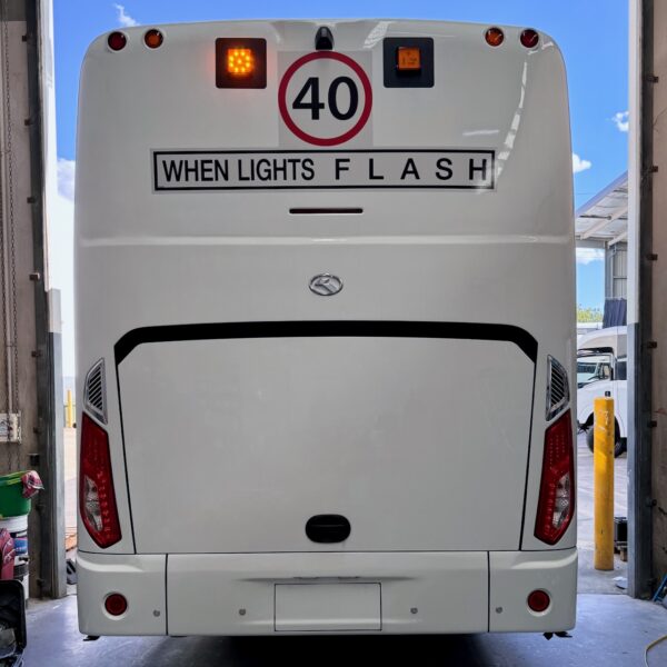 Photo of the rear of a 57-seater King Long bus with Safebus SB001A surface mount school bus lights and NSW TS150 signage installed